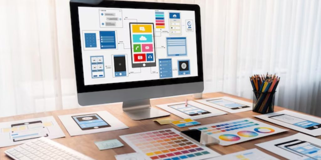 A designer reviewing wireframes and app screens on a laptop with Nigerian workspace elements in the background.
